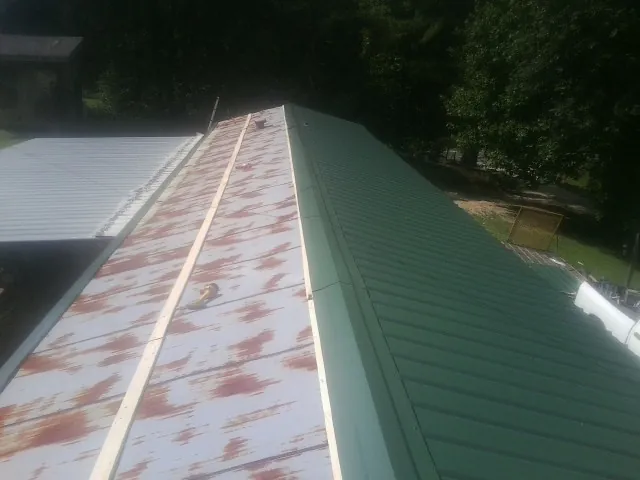 Old rusted panels beside newly installed green metal roofing — Wind Damage Roof Repair by Roofing Brothers in Loxahatchee