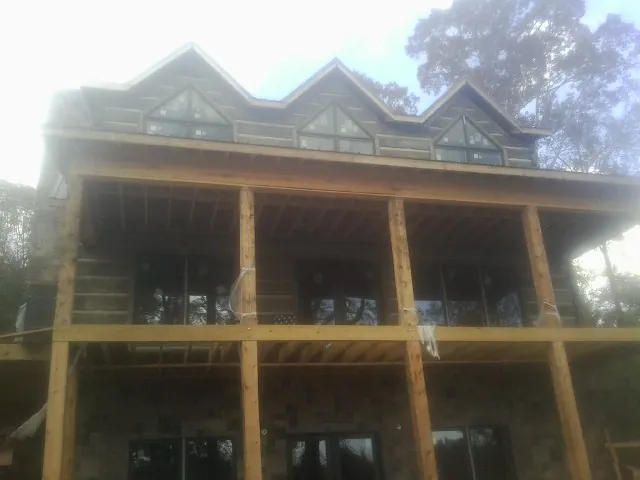 Dormers and porch framing on a large log home under construction — Roof Coating work by our crew in Loxahatchee