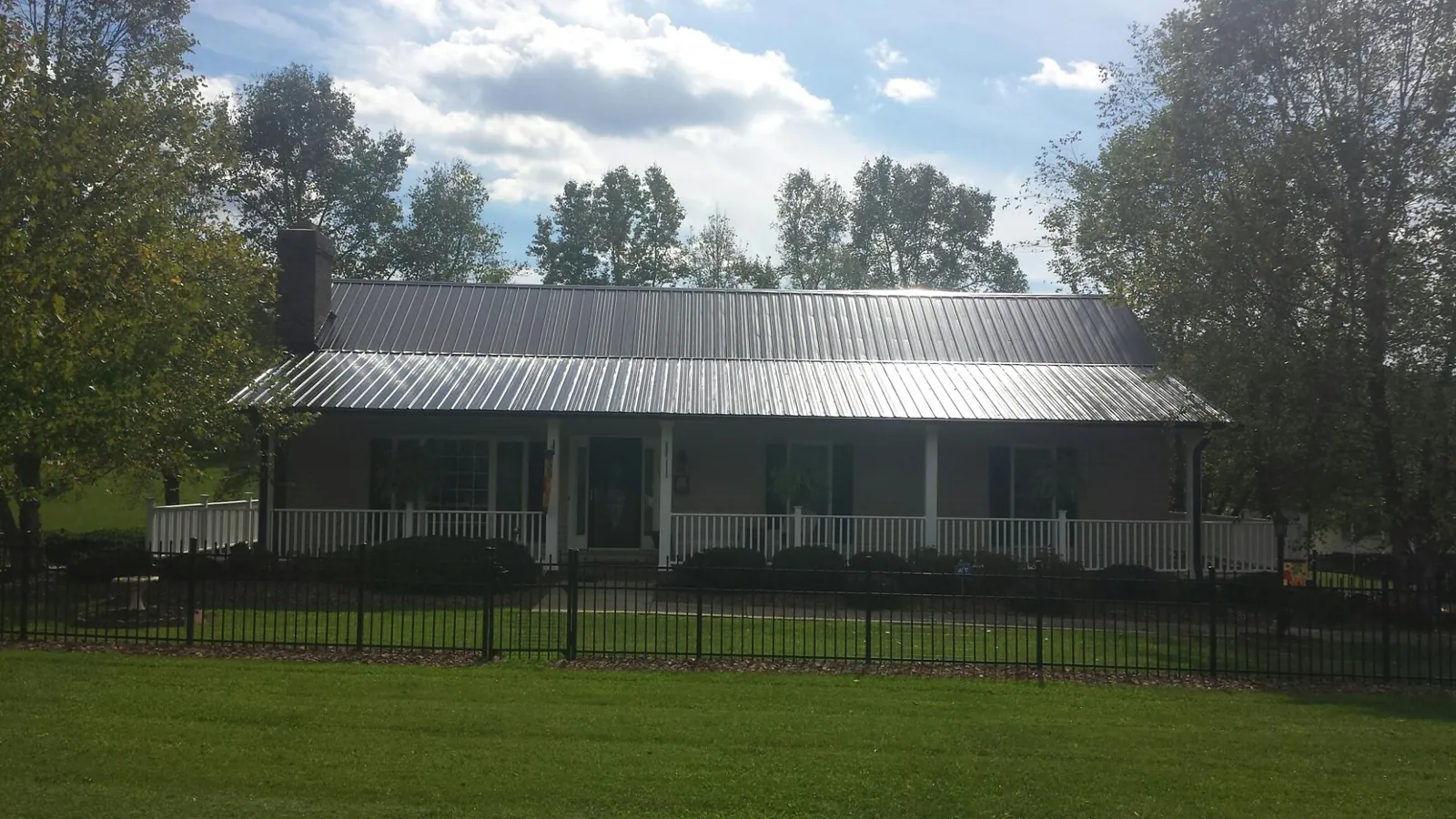 Gray metal roof on a brick ranch with a full width front porch — Gutter Guard Installation work by our crew in Loxahatchee