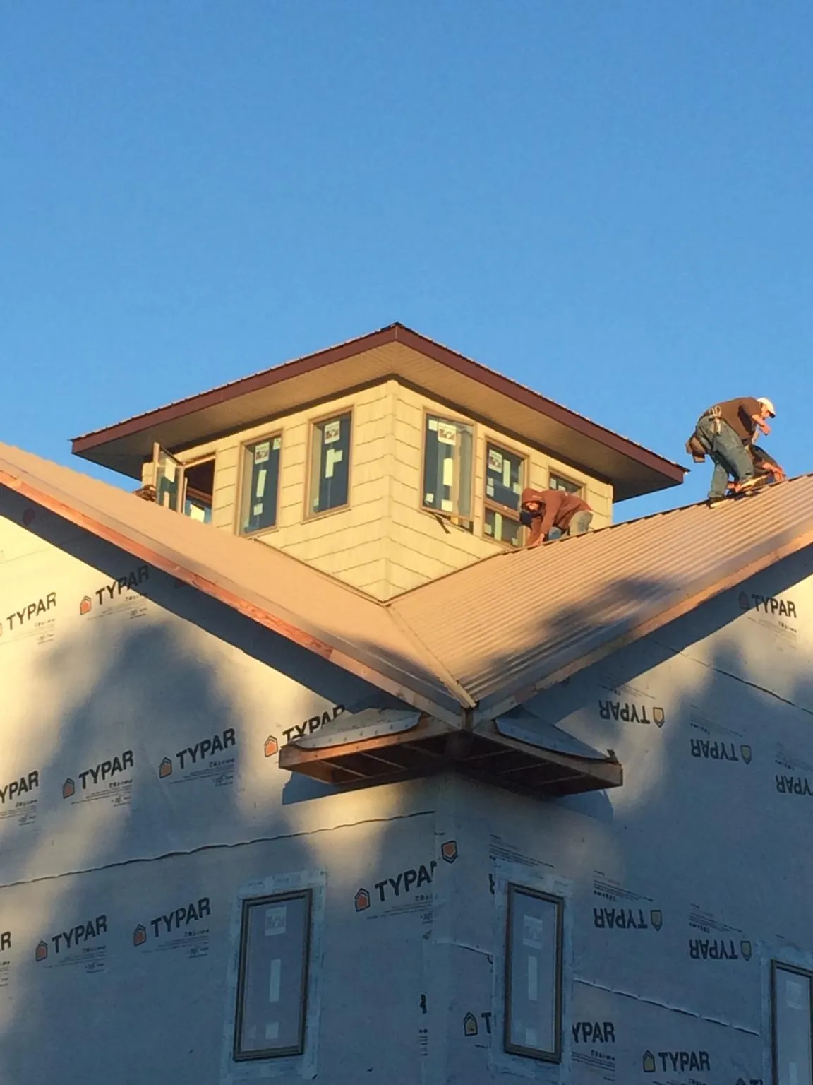 Roofers working around a rooftop cupola on a new metal roof at sunset — Roof Waterproofing in Loxahatchee by Roofing Brothers